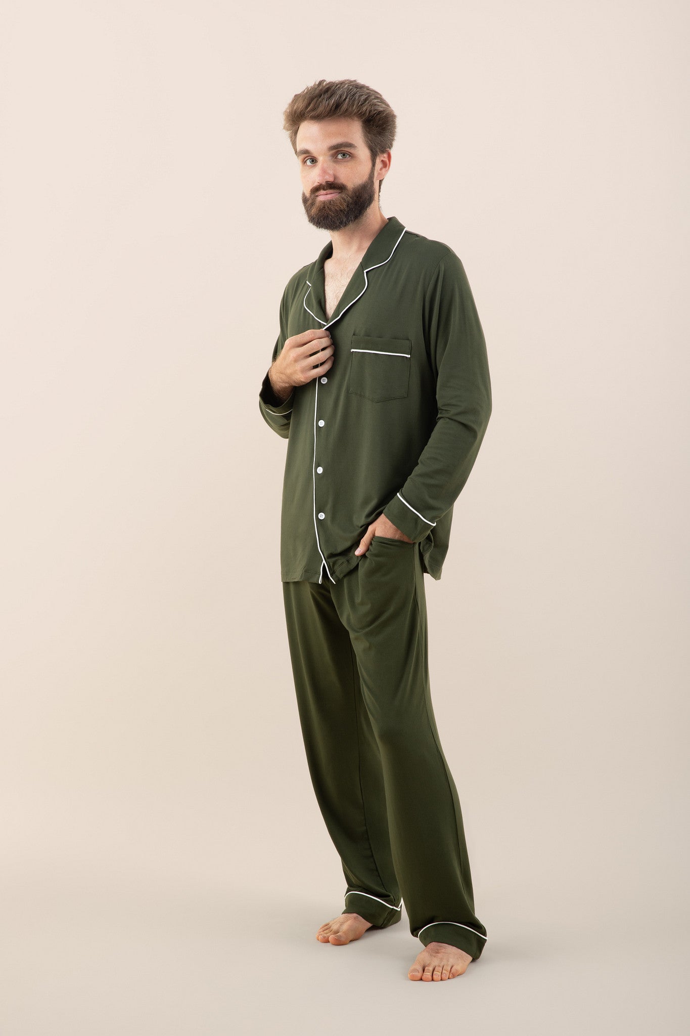 Man wearing green pajamas with white piping on a beige background