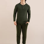 Man wearing a green long-sleeve shirt and pants on a beige background