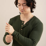 Man wearing a green long-sleeve shirt against a beige background