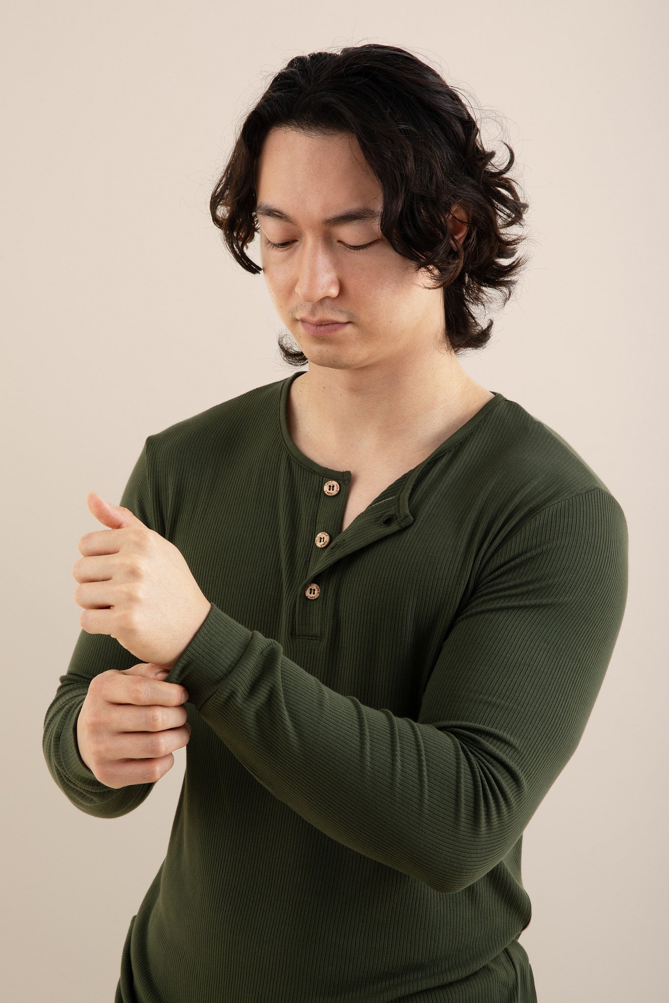 Man wearing a green long-sleeve shirt against a beige background