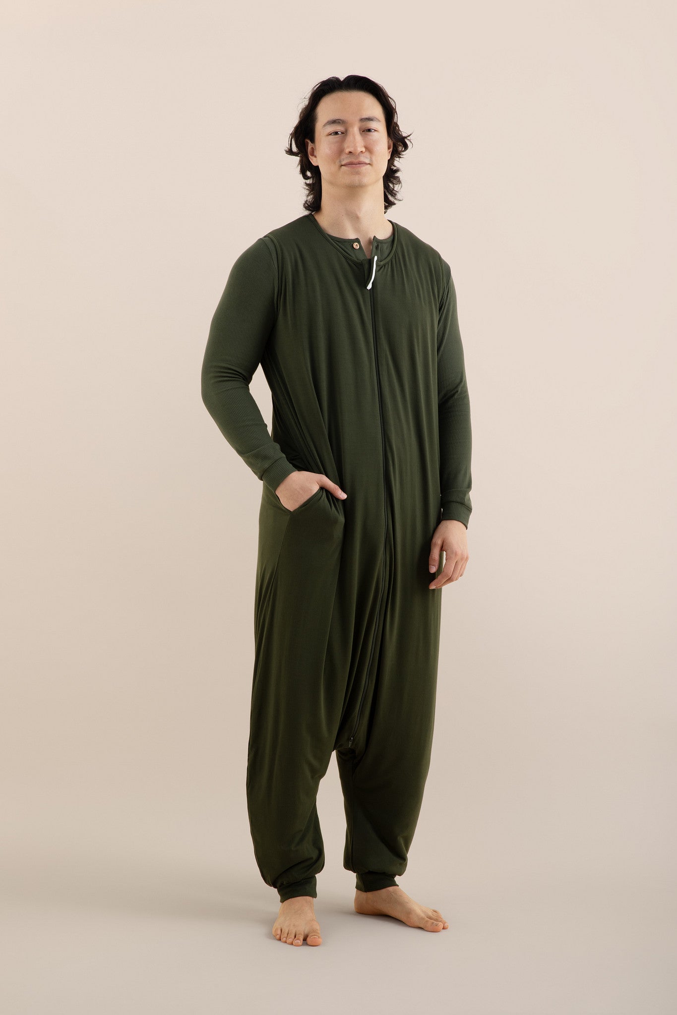 Person wearing a green onesie against a beige background