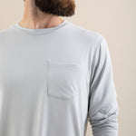 Man wearing a light gray long-sleeve shirt against a beige background