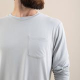 Man wearing a light gray long-sleeve shirt against a beige background