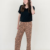 Smiling model looking to the side while wearing the Lounge Pants in Latte Leopard paired with a black V Neck