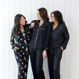 Models wearing the Kyte Long Sleeve Women's Pajama Set in Midnight  Magnolia, Midnight with Cloud Trim and Midnight Leopard