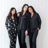 Group of 3 models wearing long sleeve button up pajamas against a white wooden wall 