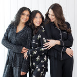 Group of 3 women modeling button up long sleeve pajamas in various black prints 