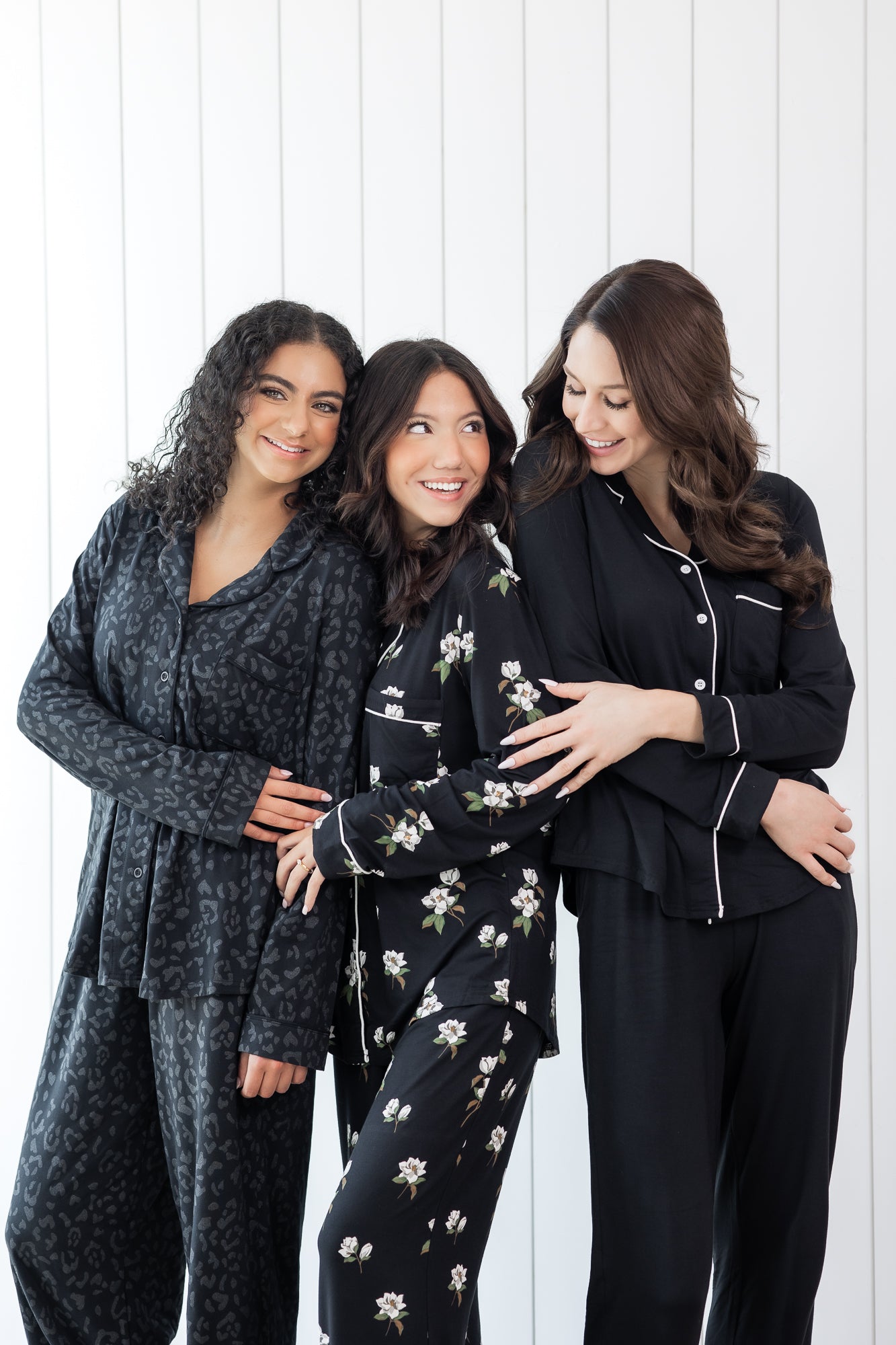 Group of 3 women modeling button up long sleeve pajamas in various black prints 