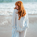 Woman modeling big mist stripe pajamas on the beach 