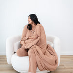 Model with eyes closed and head to the side while wrapped in the Quilt Blanket in Latte 2.5