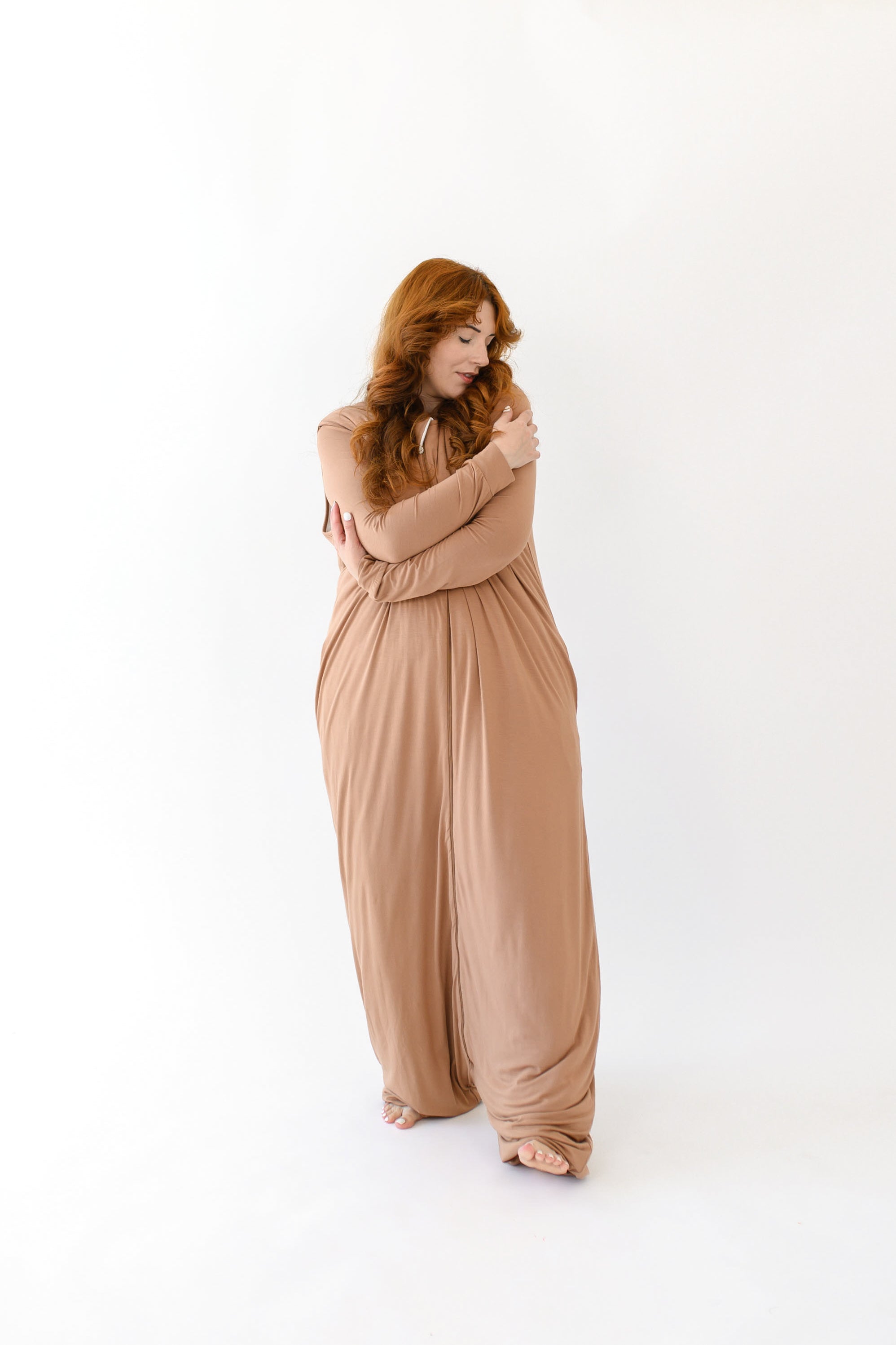 Woman with arms around herself while wearing the Adult Sleep Bag Walker in Latte