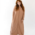 Woman standing in white room while wearing the Adult Sleep Bag Walker in Latte