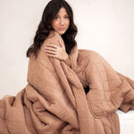 Model wrapped in the Kyte Bamboo Quilt Blanket in Latte 2.5
