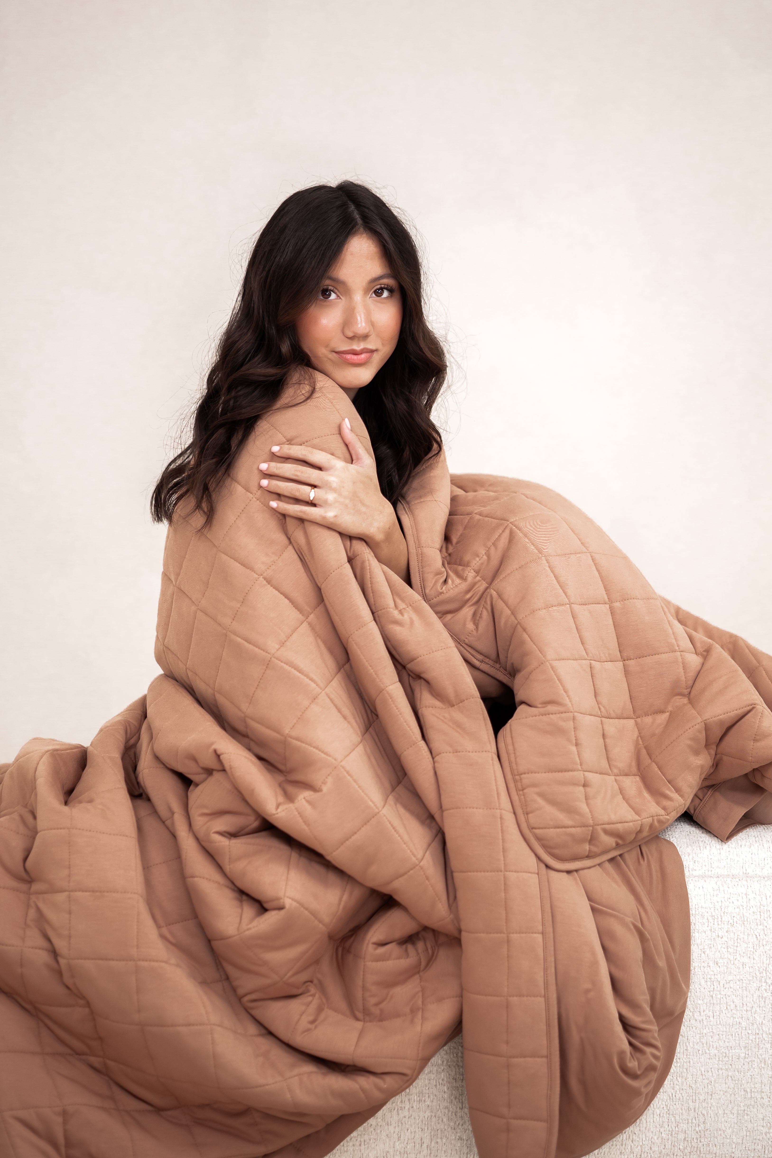 Model wrapped in the Kyte Bamboo Quilt Blanket in Latte 2.5