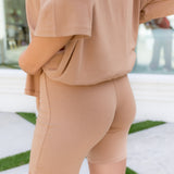 Person wearing a beige outfit with shorts on a white and green striped background