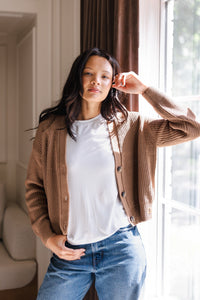 Woman with her arm propped on the window wearing a cropped cardigan in late and jeans