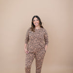 Model smiling with one hand in pocket while wearing the Kyte Latte Leopard Jogger Set 
