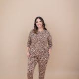 Model smiling with one hand in pocket while wearing the Kyte Latte Leopard Jogger Set 