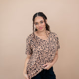 Woman modeling the Women's V Neck Tee in Latte Leopard paired with black pants