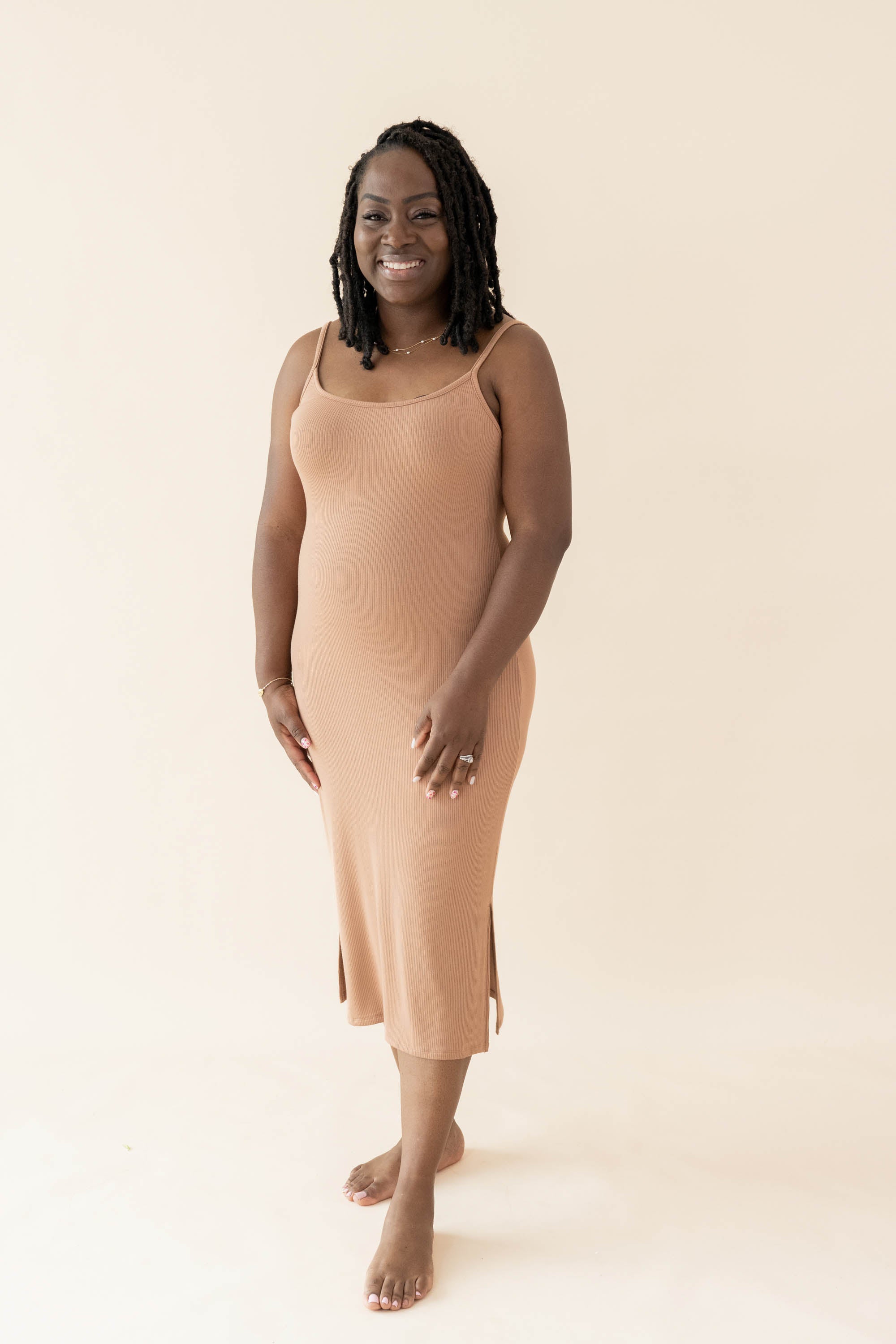 Smiling female wearing the Women's Ribbed Cami Dress in Latte with both hands on thighs