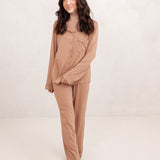 Female walking in front of a light neutral background wearing the Long-Sleeved Women's Pajama Set in Latte with Latte Trim