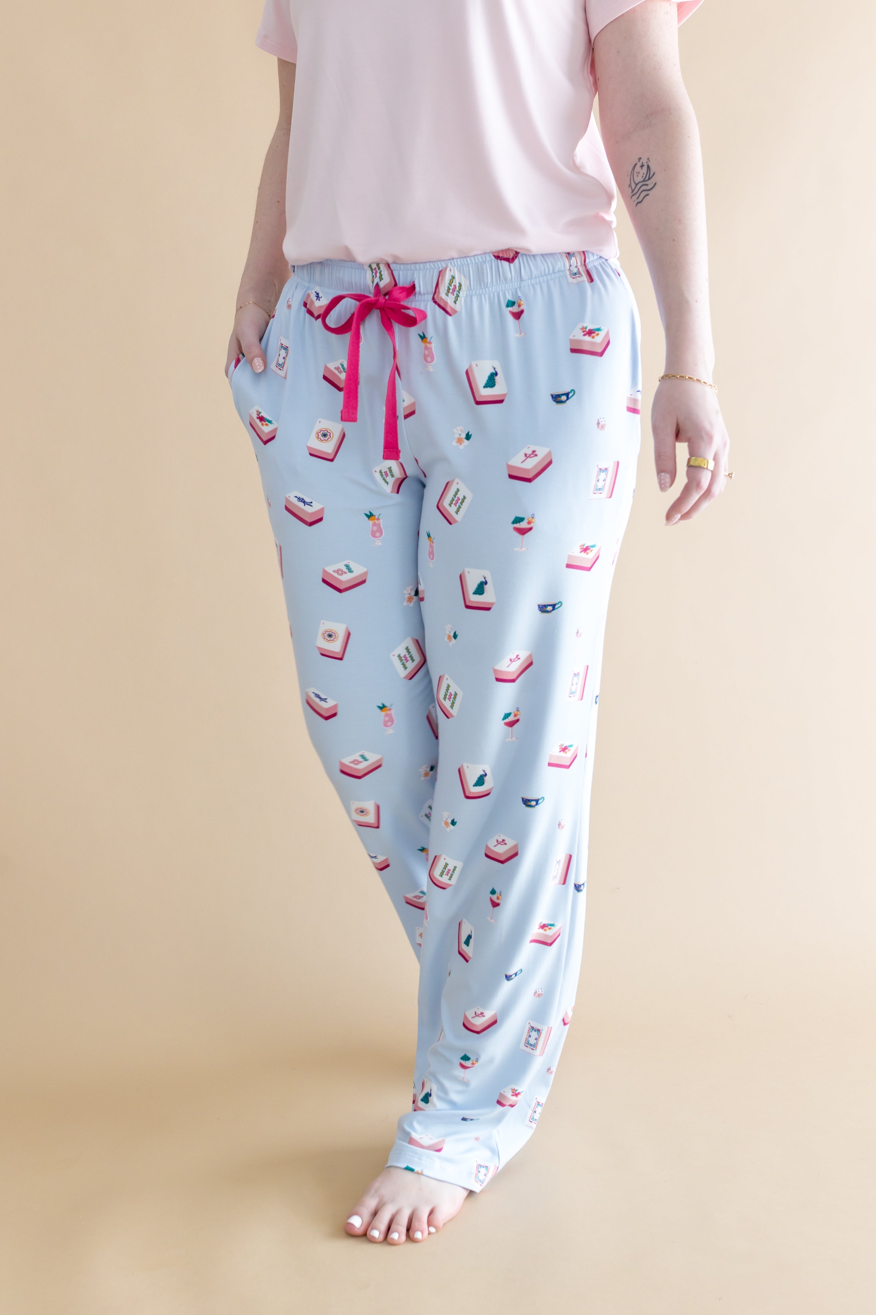 Light blue pajama pants with pink bow and Mahjong pattern on a beige background