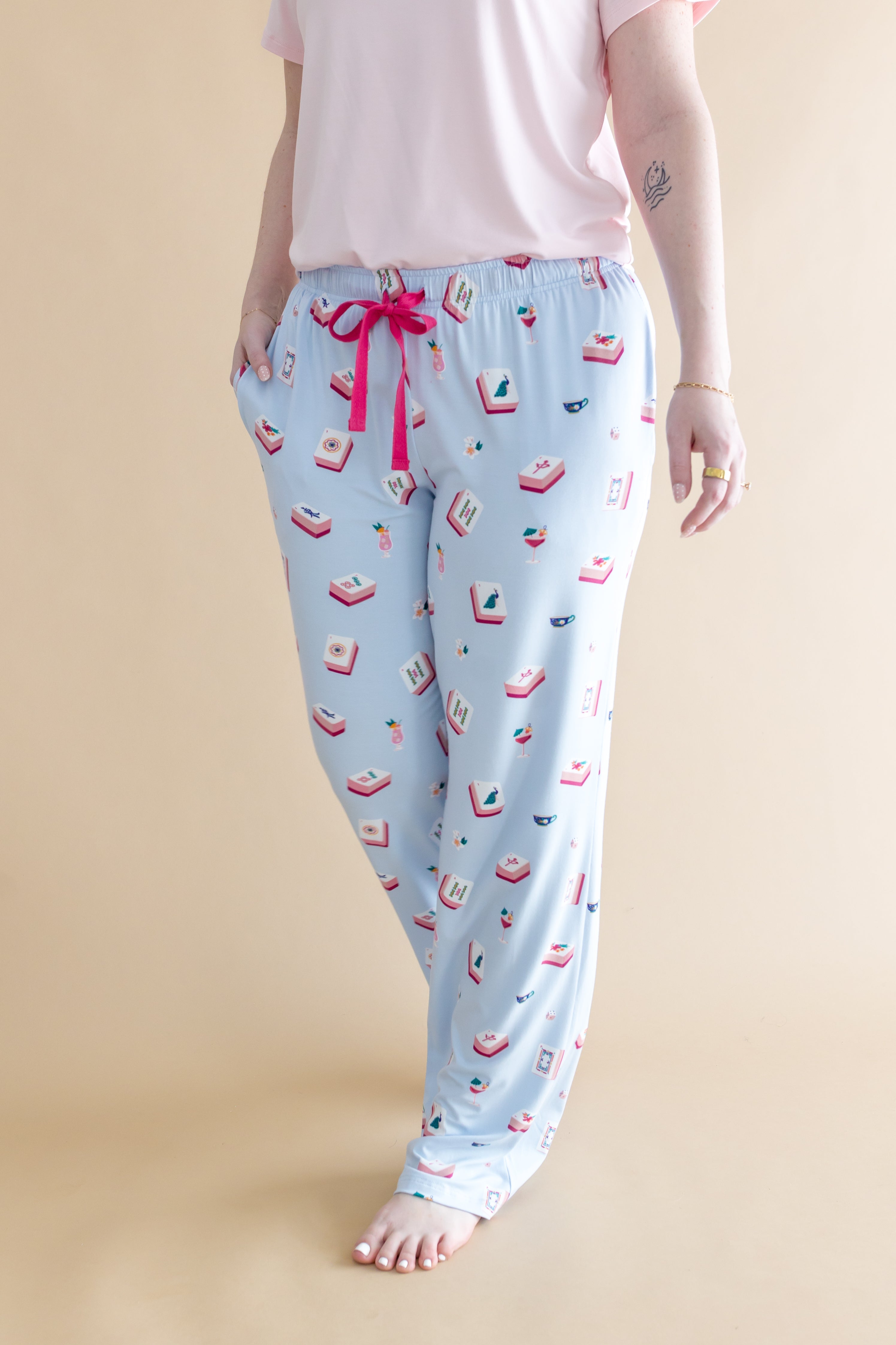 Light blue pajama pants with pink bow and Mahjong pattern on a beige background