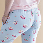 Light blue pajama pants with a pattern of Mahjong tiles and a pink shirt on a beige background