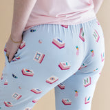 Light blue pajama pants with a pattern of Mahjong tiles and a pink shirt on a beige background