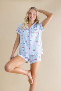 Woman wearing a light blue pajama set with pink accents and a Mahjong pattern on a beige background