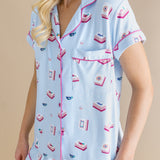 Woman wearing a light blue pajama set with pink accents on a beige background