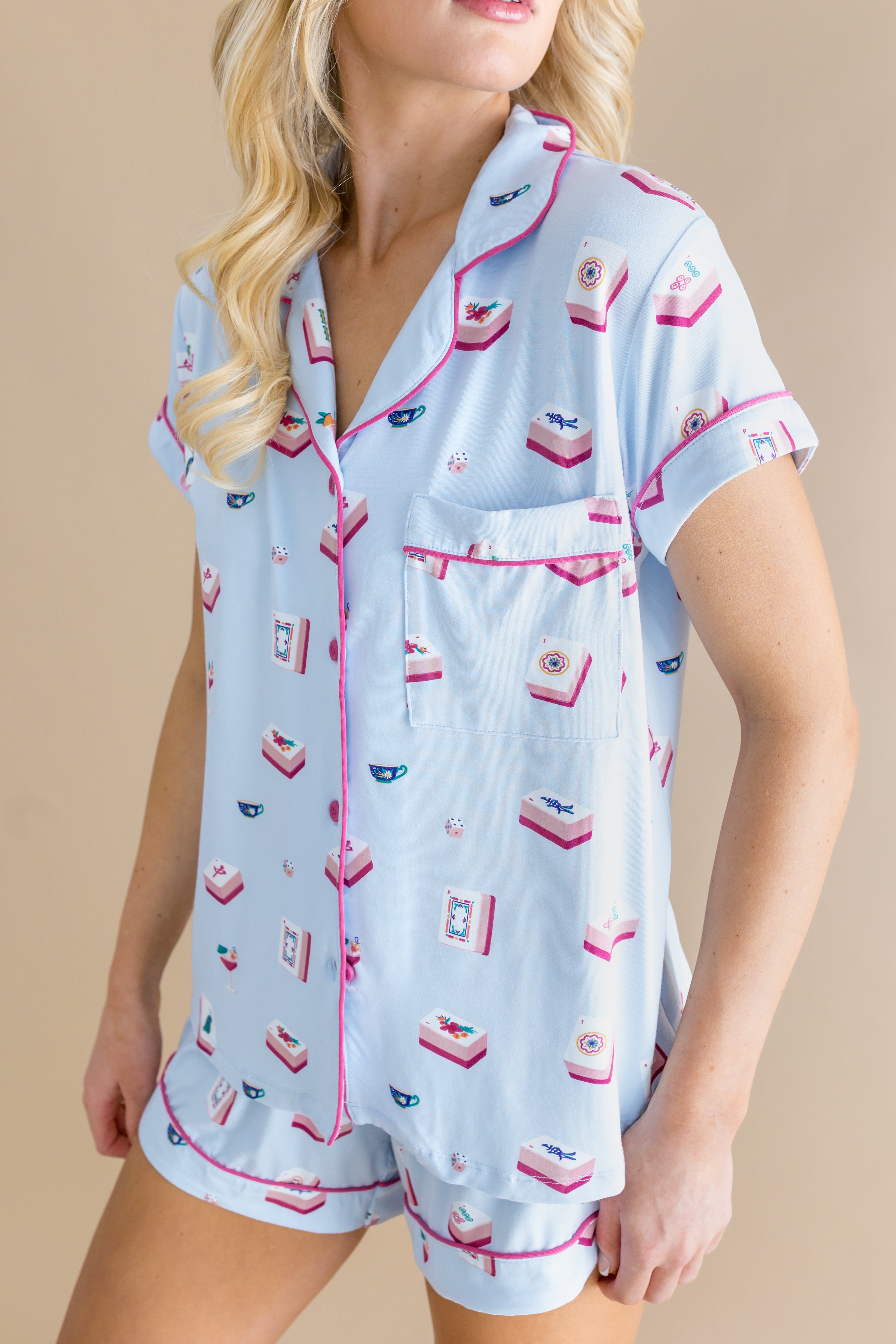 Woman wearing a light blue pajama set with pink accents on a beige background