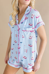 Woman wearing a light blue pajama set with pink accents on a beige background