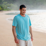 Male model on the beach in the sand wearing the Men's Crew Neck Tee in Makai with Khaki colored shorts