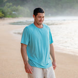 Male model on the beach in the sand wearing the Men's Crew Neck Tee in Makai with Khaki colored shorts
