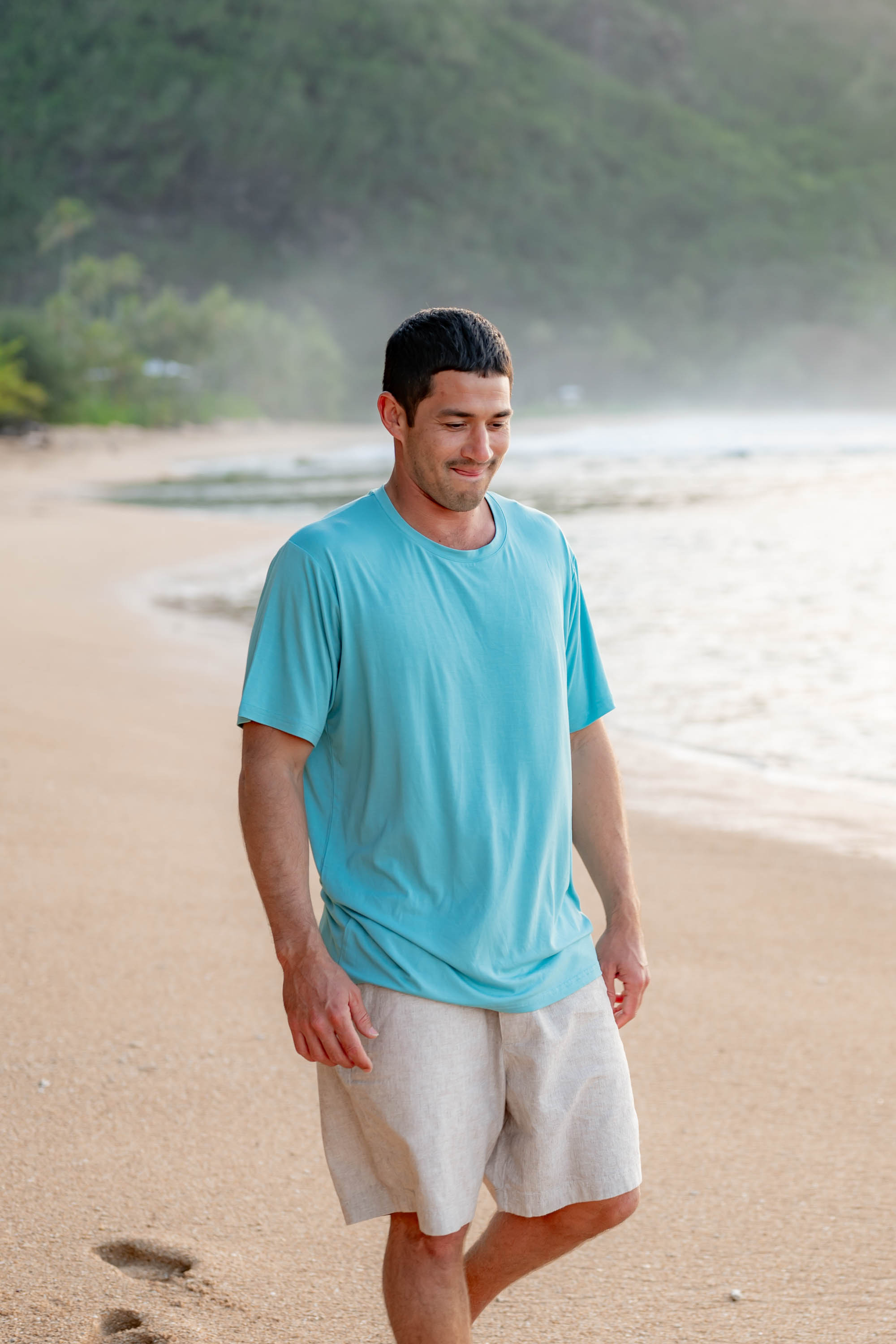 Male model on the beach in the sand wearing the Men's Crew Neck Tee in Makai with Khaki colored shorts