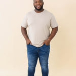 Male model wearing the Men's Crew Neck Tee in Almond with medium wash jeans