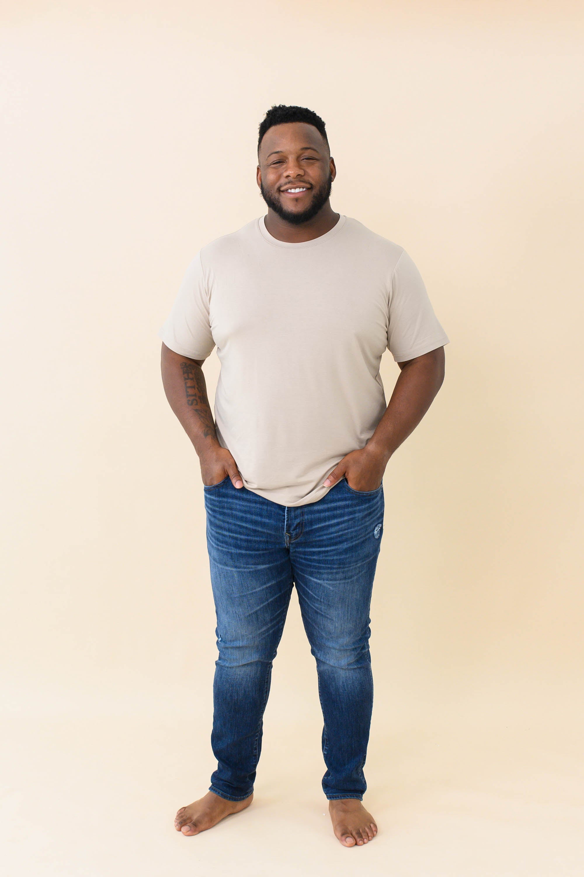 Male model wearing the Men's Crew Neck Tee in Almond with medium wash jeans