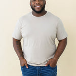 Male model wearing the Men's Crew Neck Tee in Almond with medium wash jeans