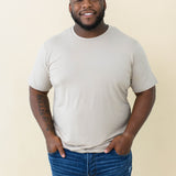Male model wearing the Men's Crew Neck Tee in Almond with medium wash jeans
