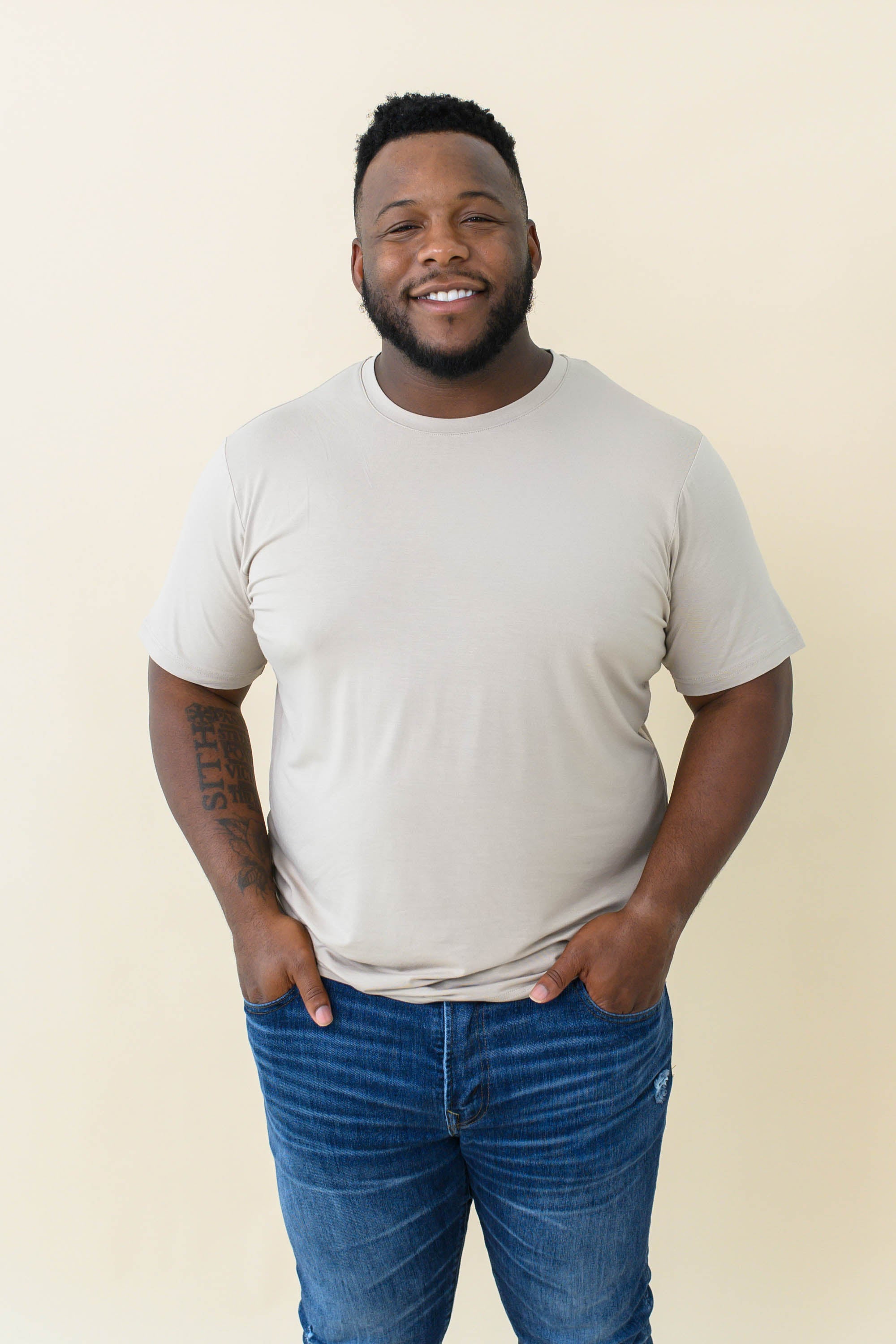 Male model wearing the Men's Crew Neck Tee in Almond with medium wash jeans