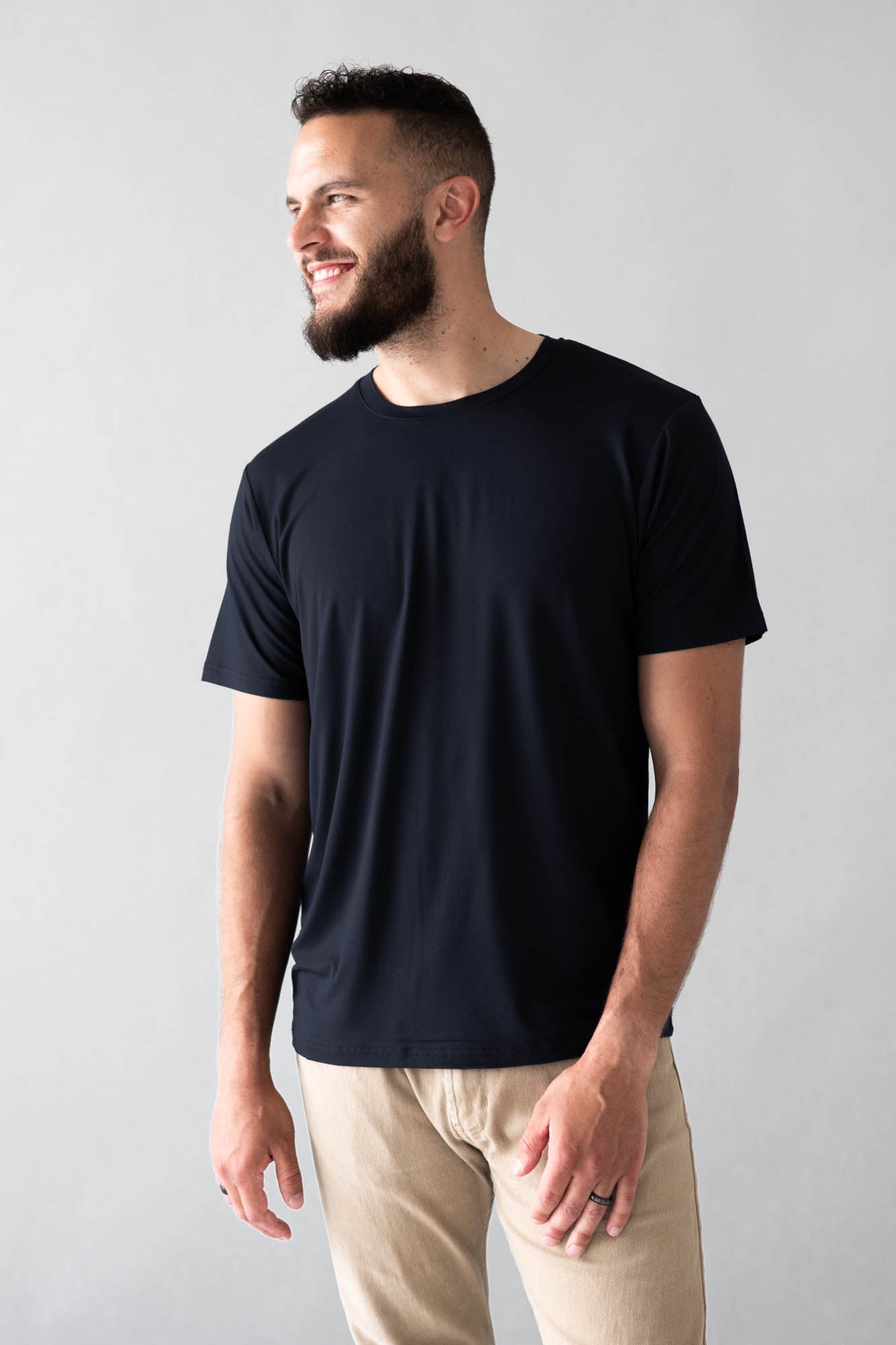 Smiling male wearing the Men's Crew Neck Tee in Midnight in Khaki colored pants