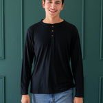 Smiling model in the Men's Long Sleeve Henley Top in Midnight and medium wash pants