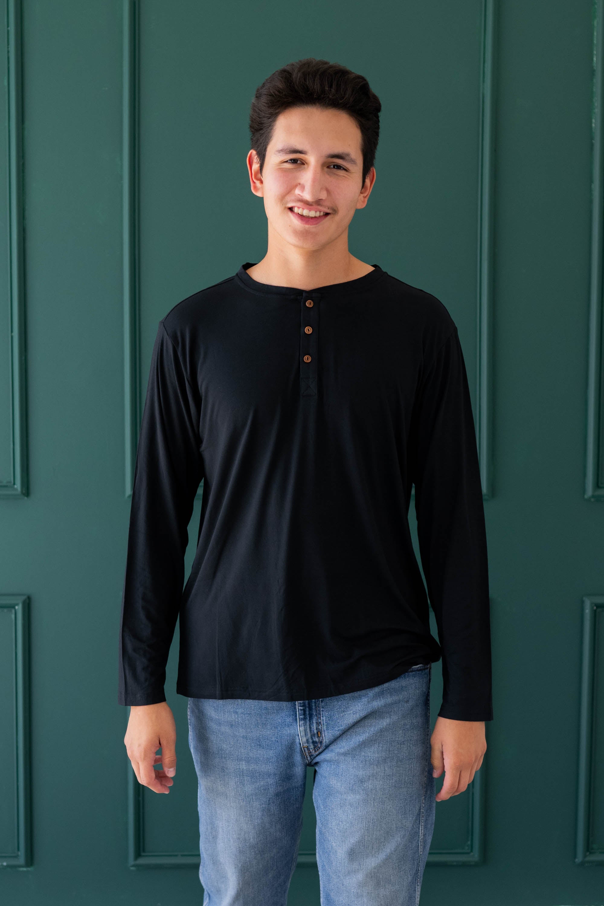 Smiling model in the Men's Long Sleeve Henley Top in Midnight and medium wash pants