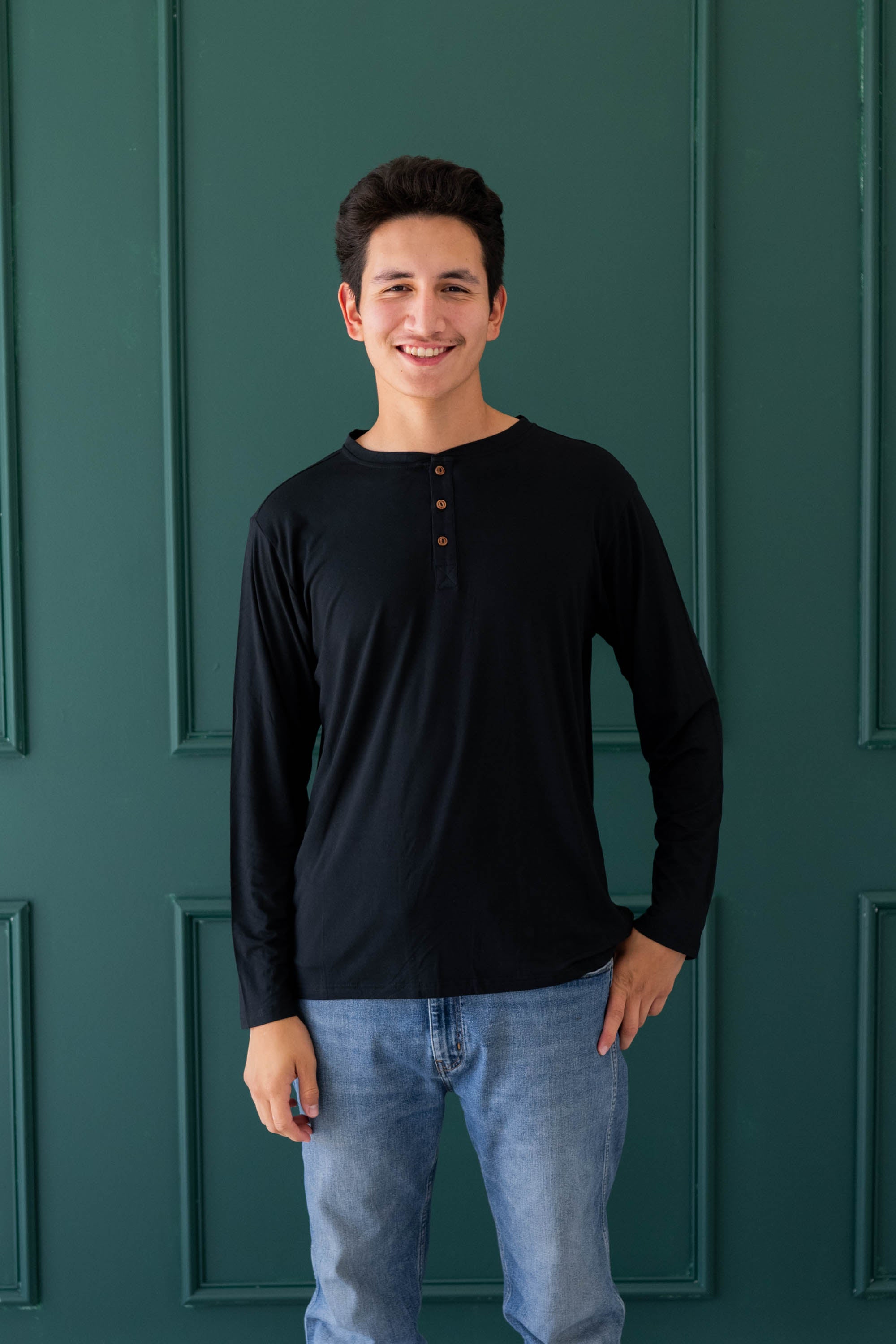 Male model wearing the Men's Long Sleeve Henley Top in Midnight and medium wash jeans