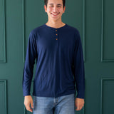 Male model wearing the Men's Long Sleeve Henley Top in Navy and medium wash jeans
