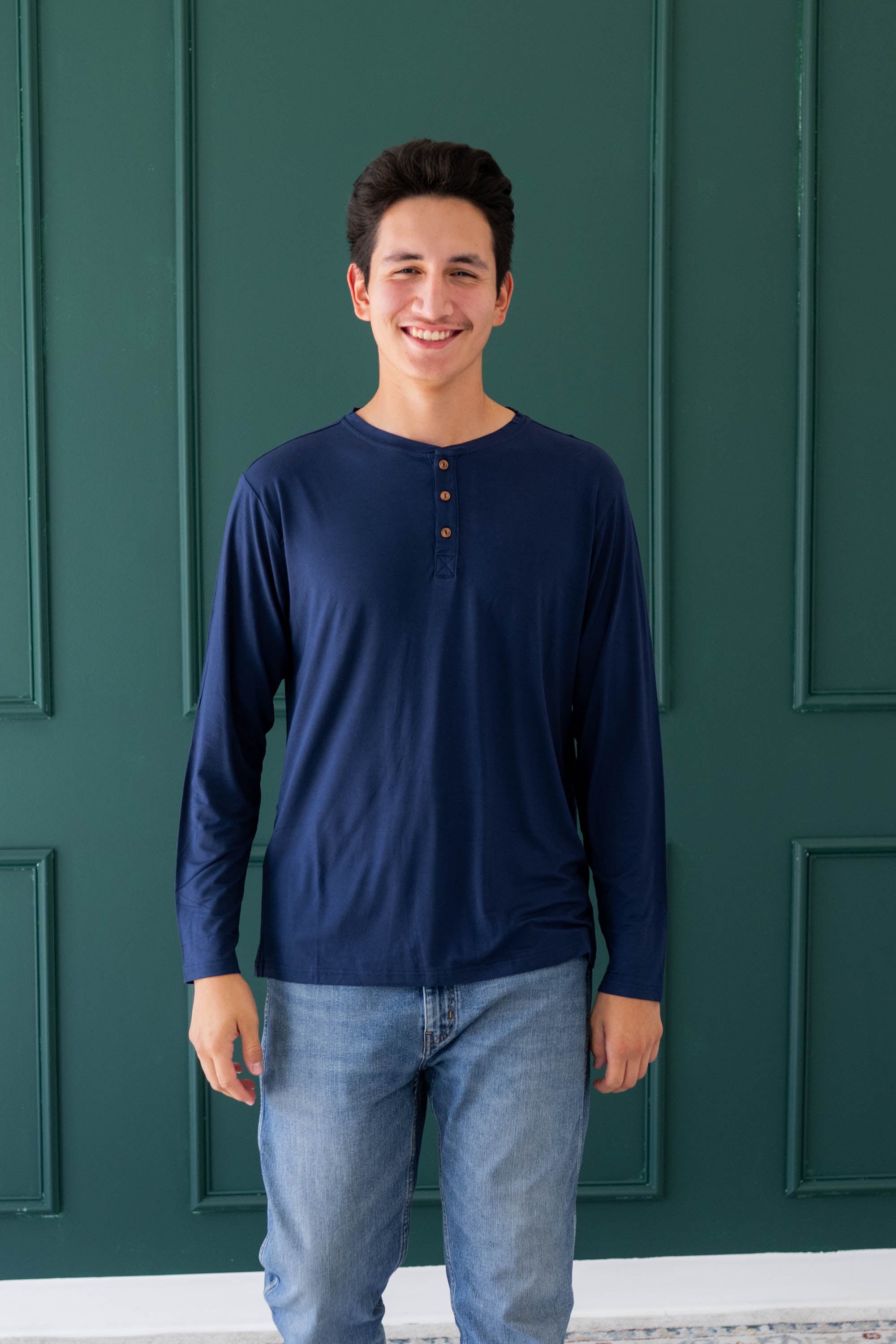 Male model wearing the Men's Long Sleeve Henley Top in Navy and medium wash jeans