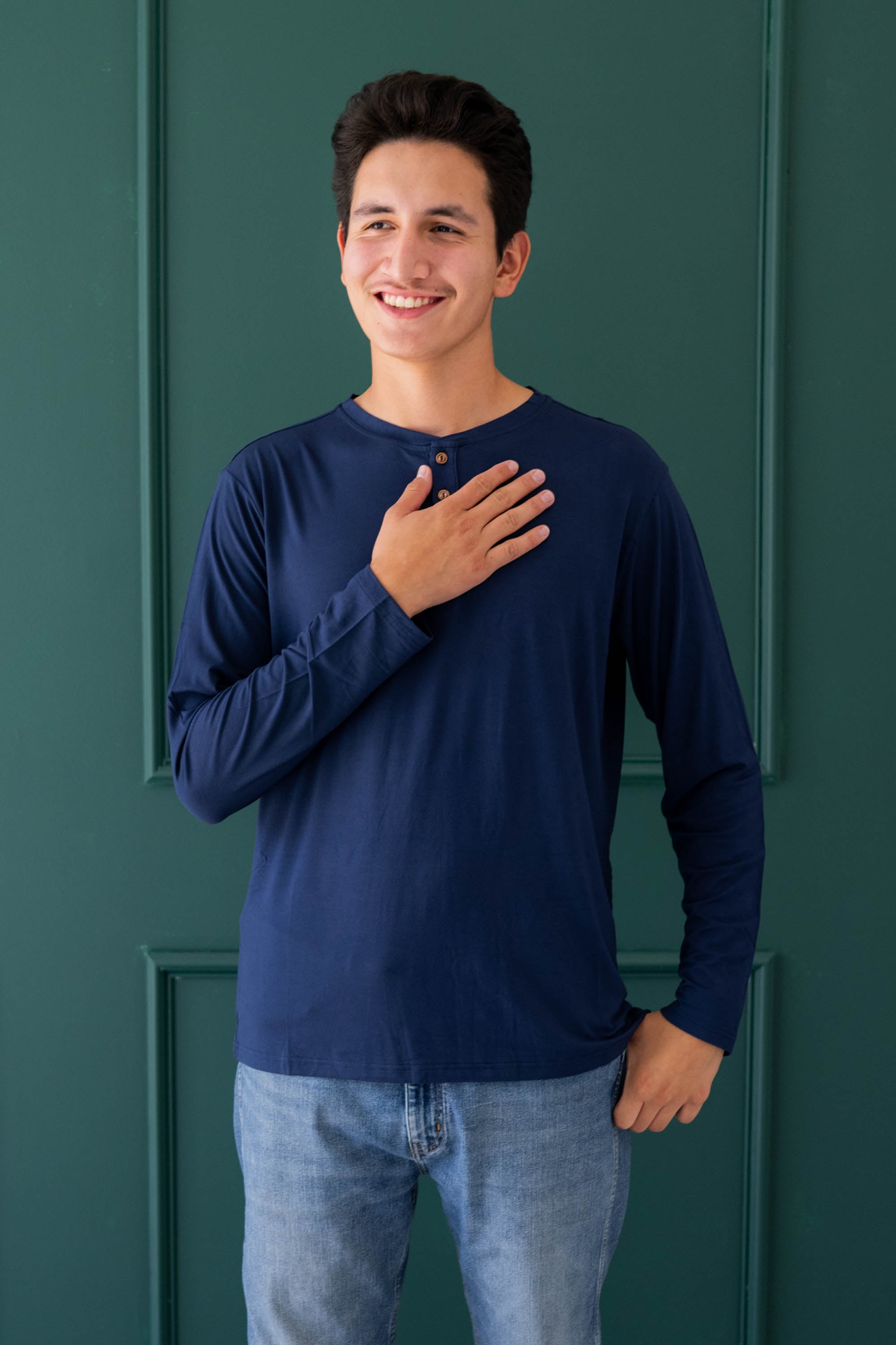 Smiling male wearing the Men's Long Sleeve Henley Top in Navy paired with light wash jeans