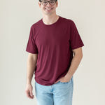 Male model wearing Men's Crew Neck Tee in Burgundy with hand in pocket of light-wash jeans