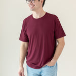 Male model wearing Men's Crew Neck Tee in Burgundy paired with jeans